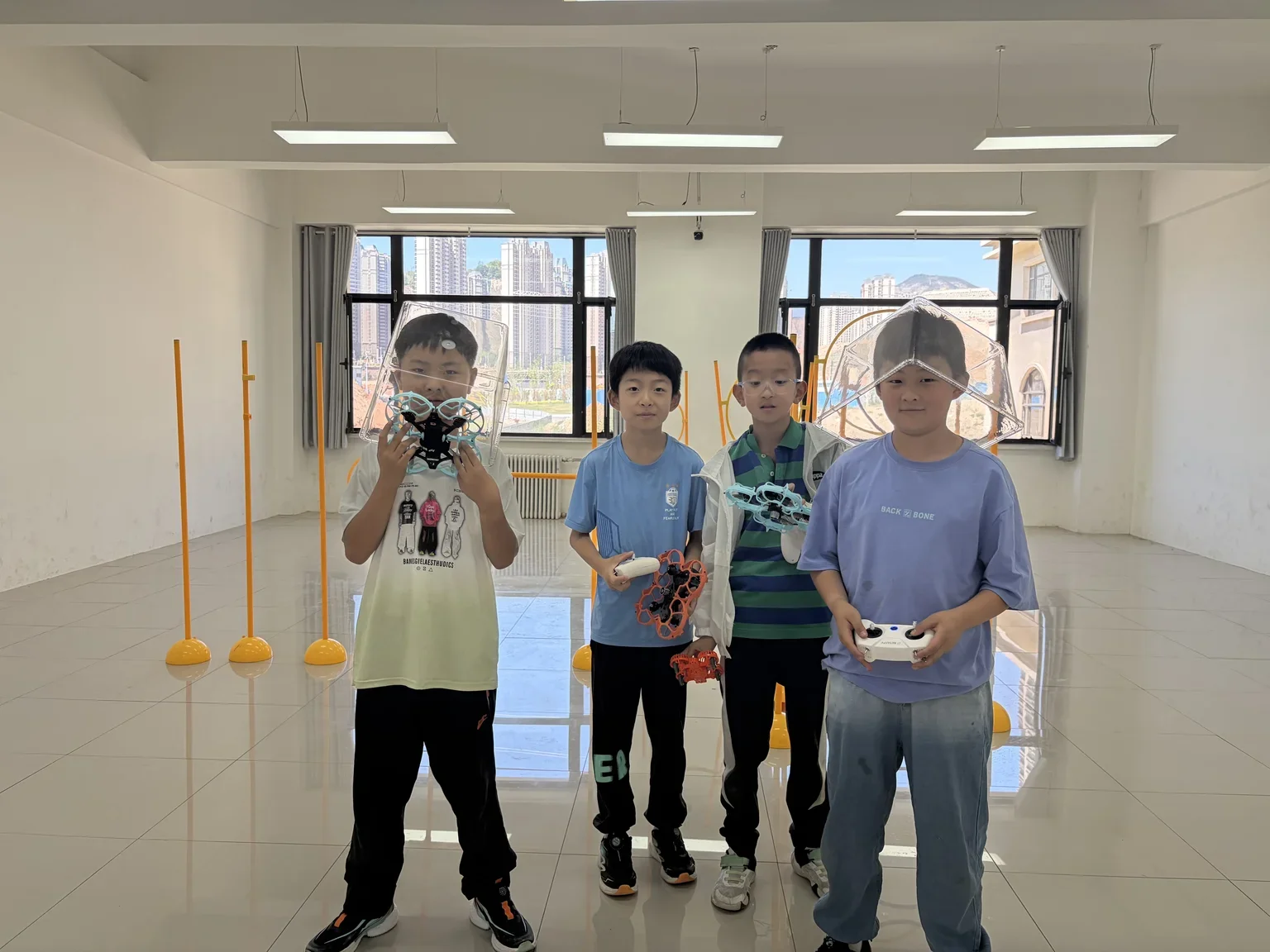 左家湾学校小队员手持无人机设备、遥控器与安全防护网头盔合影